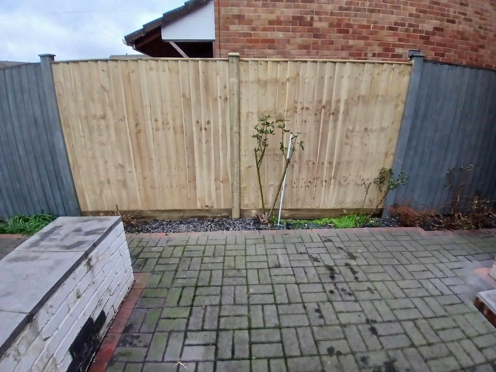 A new closeboard fence section set between older painted panels
