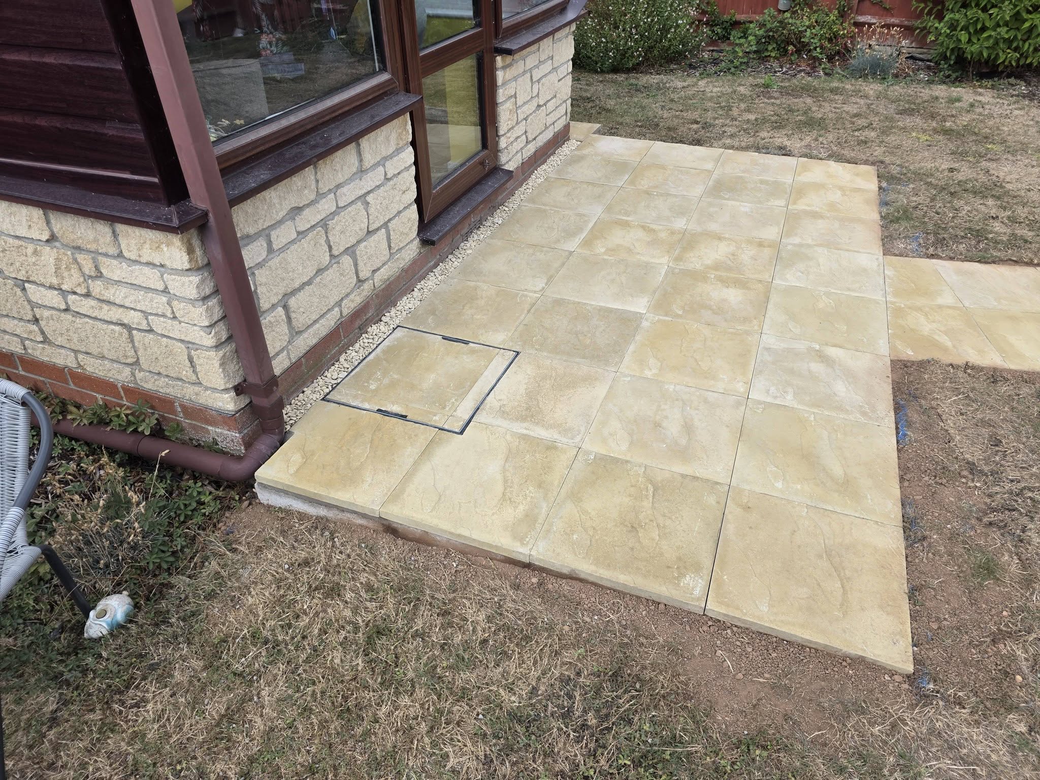 Buff slab patio and path beside a conservatory