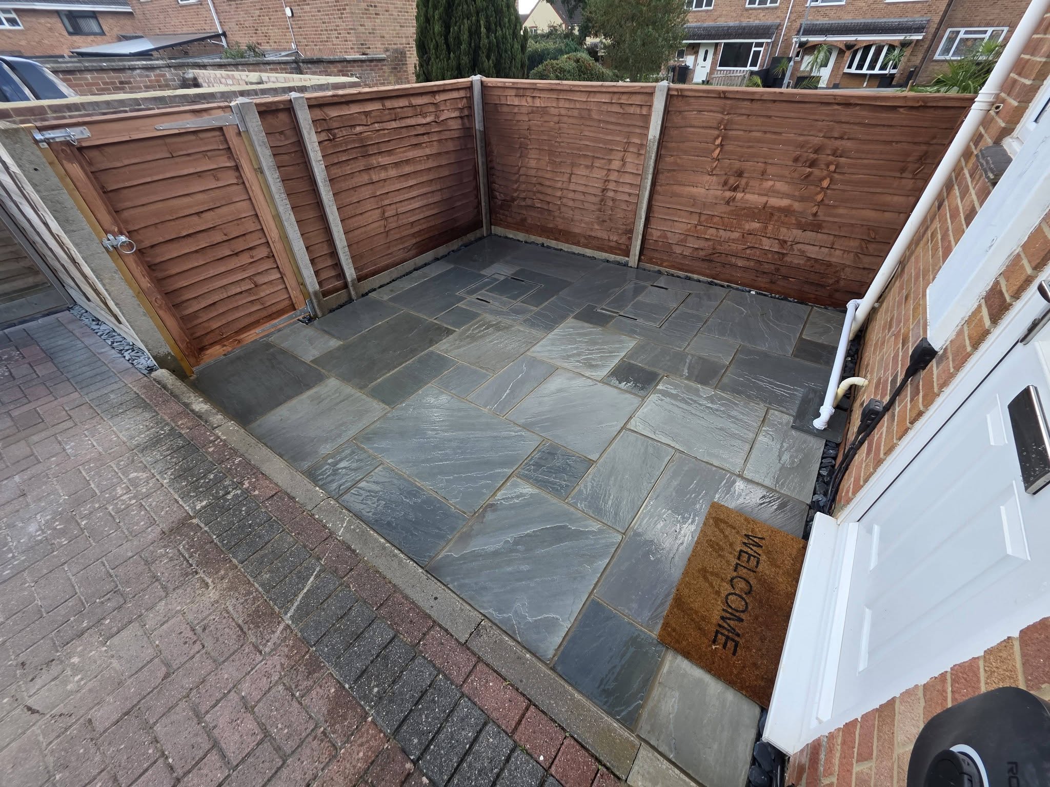 Dark grey stone patio in a fenced courtyard with a gate
