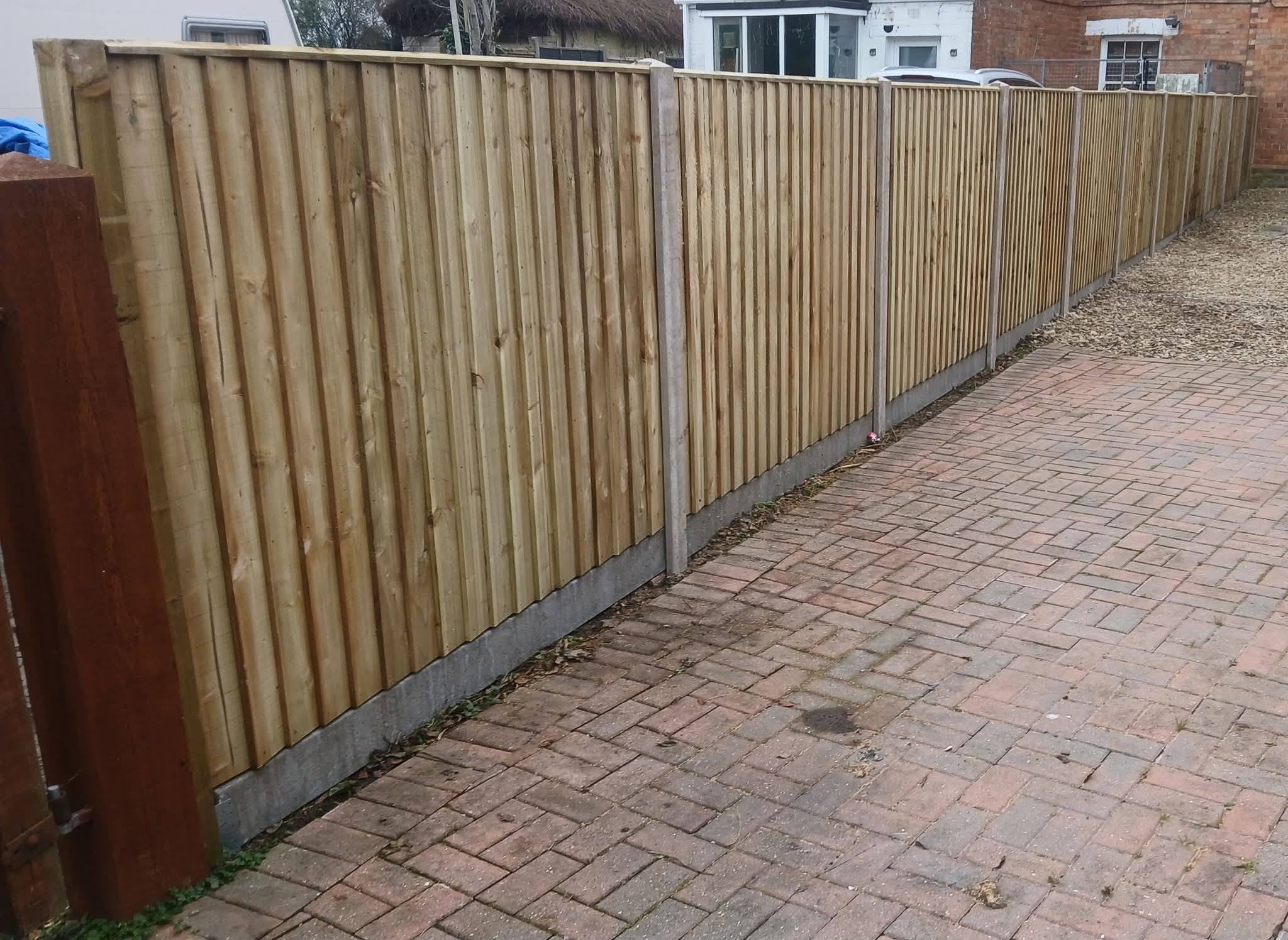 New closeboard fence on concrete posts along a block-paved drive